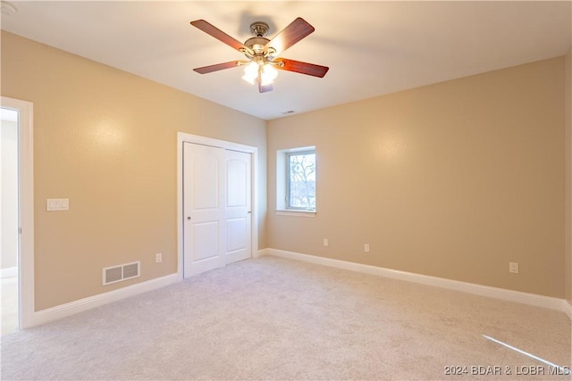 unfurnished bedroom featuring light carpet, a closet, and ceiling fan