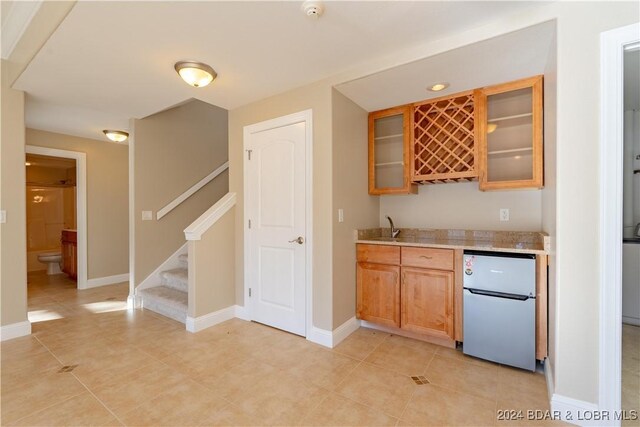 550 Grand Cove Rd, Porto Cima, MO 65079 - indoor wet bar with freestanding refrigerator, baseboards, stairway, and light tile patterned floors