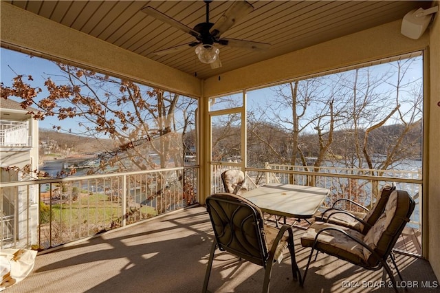 sunroom / solarium with a ceiling fan, a mountain view, outdoor dining area, and healthy amount of natural light