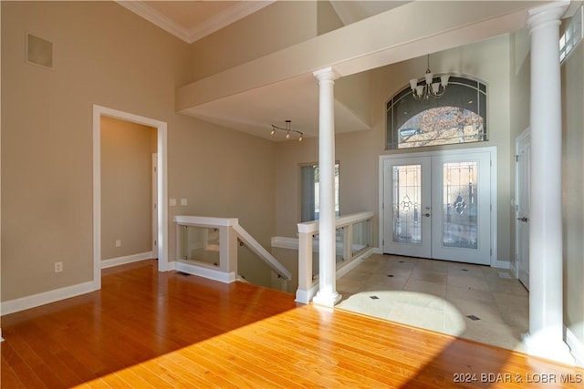 entryway with french doors, a notable chandelier, crown molding, a towering ceiling, and wood-type flooring