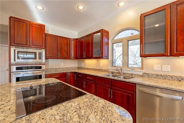 kitchen with light stone countertops, stainless steel appliances, and sink