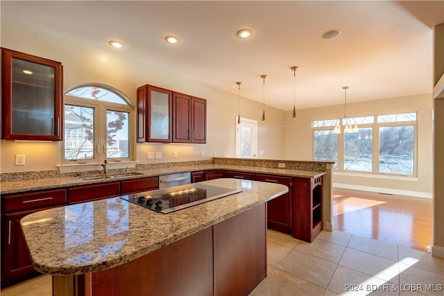 kitchen with black electric stovetop, sink, light tile patterned floors, decorative light fixtures, and a kitchen island