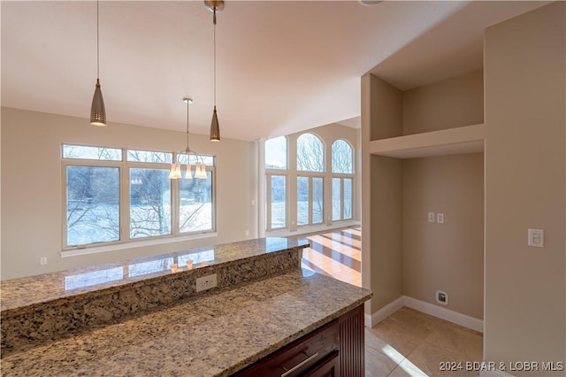 kitchen featuring pendant lighting, a notable chandelier, light stone countertops, and light tile patterned floors