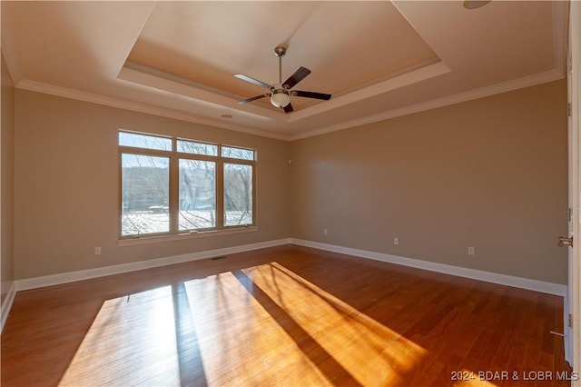 empty room with a tray ceiling, crown molding, ceiling fan, and dark hardwood / wood-style floors