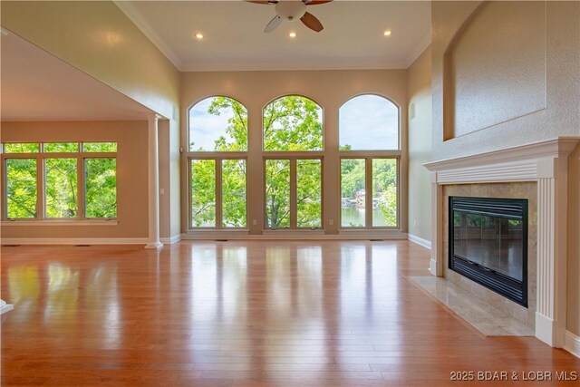 550 Grand Cove Rd, Porto Cima, MO 65079 - unfurnished living room featuring a tiled fireplace, plenty of natural light, a ceiling fan, light wood-style flooring, and ornamental molding
