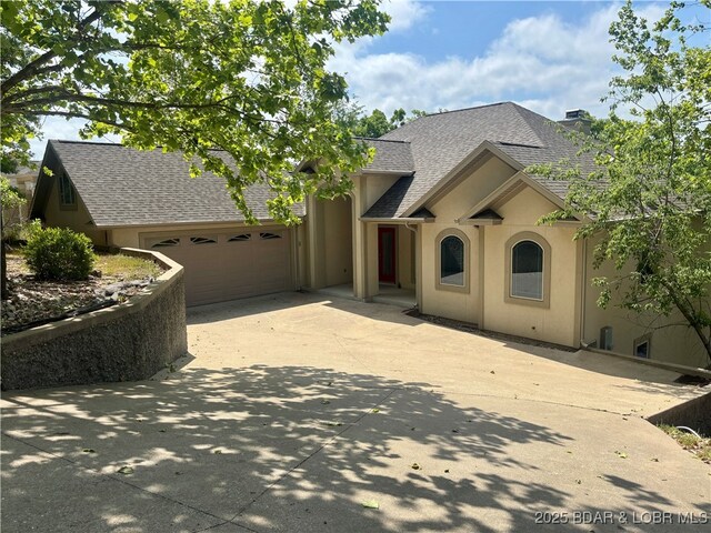 550 Grand Cove Rd, Porto Cima, MO 65079 - view of front of home featuring driveway, a garage, roof with shingles, stucco siding, and a chimney