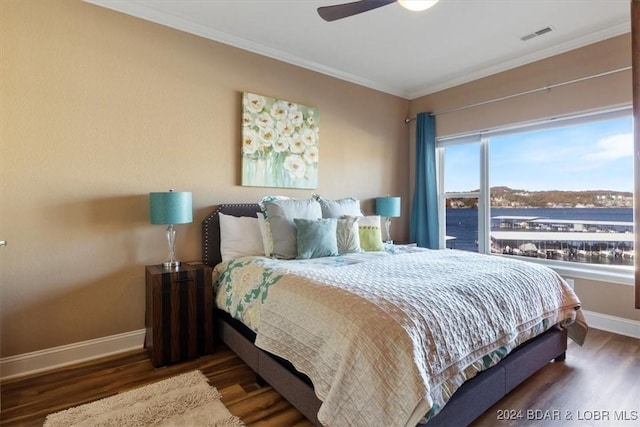 bedroom featuring dark hardwood / wood-style flooring, a water view, ceiling fan, and crown molding