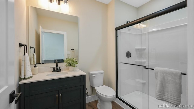 bathroom featuring hardwood / wood-style floors, vanity, toilet, and a shower with door