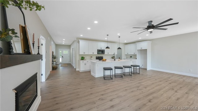 kitchen featuring white cabinets, a center island with sink, and light hardwood / wood-style floors