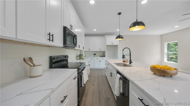 kitchen featuring light stone countertops, black appliances, sink, white cabinetry, and hanging light fixtures