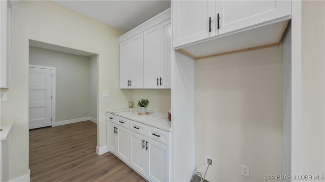 kitchen featuring white cabinetry, hardwood / wood-style floors, and light stone counters