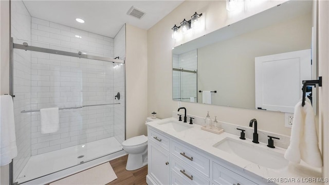 bathroom with hardwood / wood-style floors, vanity, toilet, and a shower with shower door