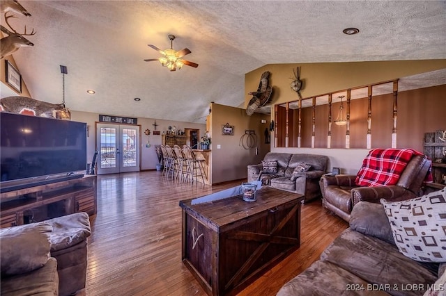 living room with a textured ceiling, hardwood / wood-style floors, and vaulted ceiling