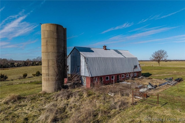 back of property featuring a yard, a rural view, and an outdoor structure