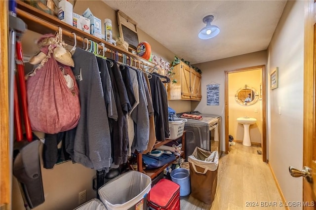 clothes washing area featuring sink, washer and dryer, a textured ceiling, and light wood-type flooring