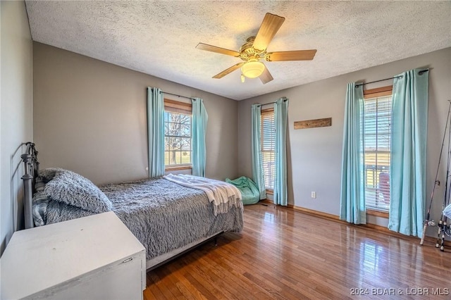 bedroom featuring ceiling fan, wood-type flooring, and a textured ceiling