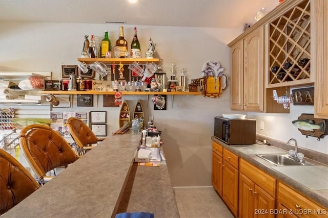 bar featuring sink and light tile patterned floors