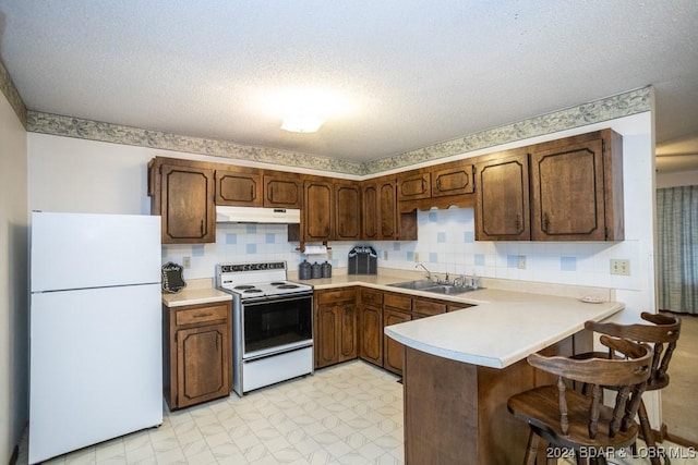 kitchen featuring sink, white appliances, tasteful backsplash, a textured ceiling, and kitchen peninsula