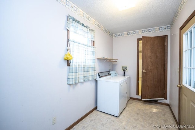 clothes washing area featuring plenty of natural light, washing machine and clothes dryer, and a textured ceiling