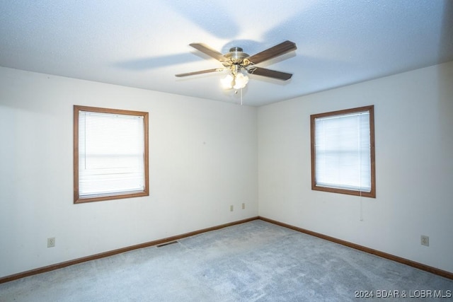 empty room with ceiling fan, a textured ceiling, a healthy amount of sunlight, and carpet flooring