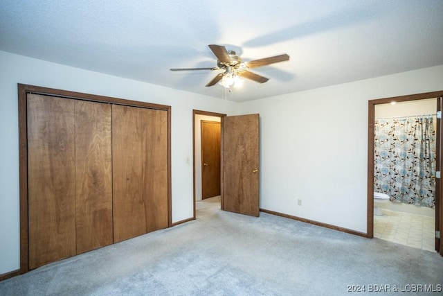 unfurnished bedroom featuring ensuite bath, light colored carpet, ceiling fan, a textured ceiling, and a closet