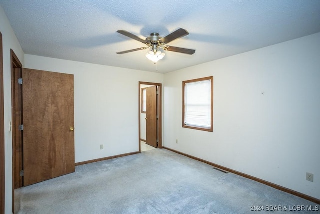 carpeted spare room featuring ceiling fan and a textured ceiling