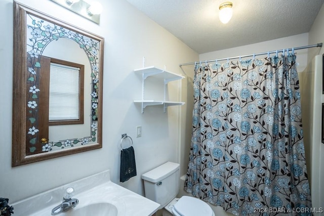 bathroom with vanity, curtained shower, toilet, and a textured ceiling