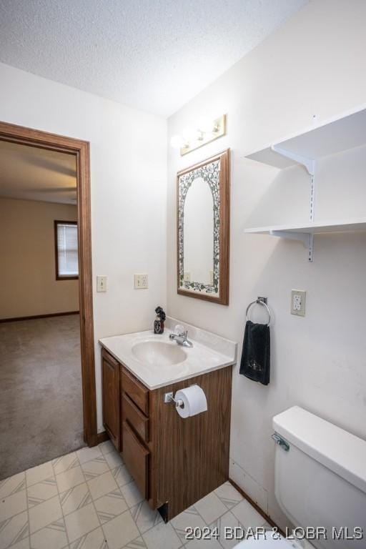 bathroom featuring vanity, a textured ceiling, and toilet