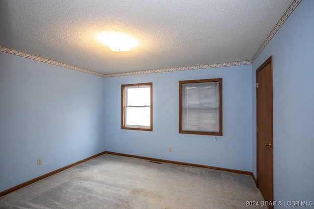 carpeted spare room featuring a textured ceiling