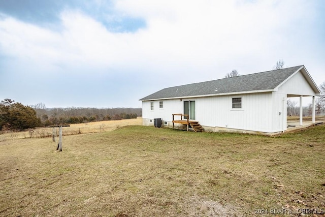 rear view of property with a yard and central air condition unit