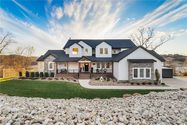 modern farmhouse style home featuring a front lawn, covered porch, and a garage