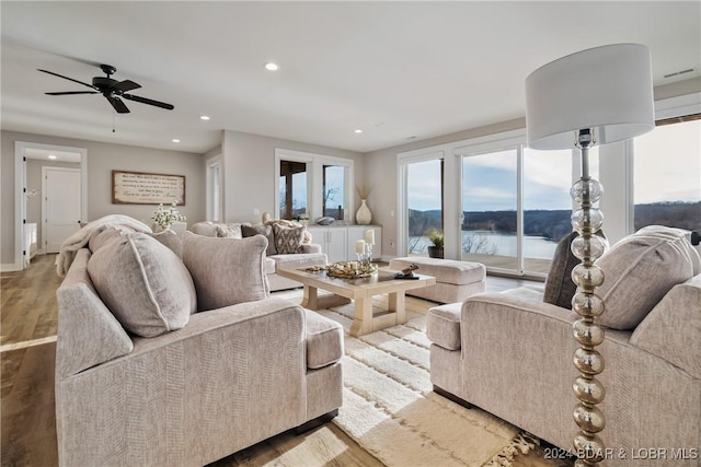 living room with hardwood / wood-style floors, ceiling fan, and a water view