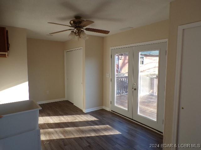 empty room featuring french doors, ceiling fan, and dark wood-type flooring