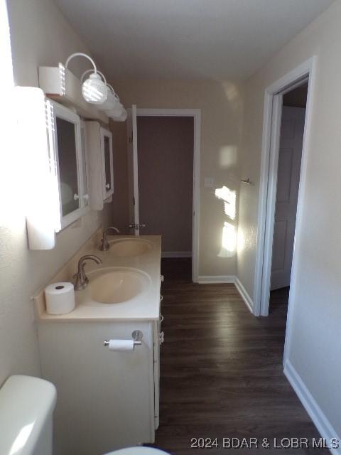 bathroom with toilet, vanity, and hardwood / wood-style flooring