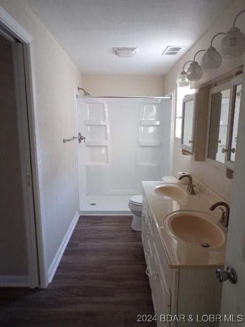 bathroom with toilet, hardwood / wood-style floors, vanity, and walk in shower