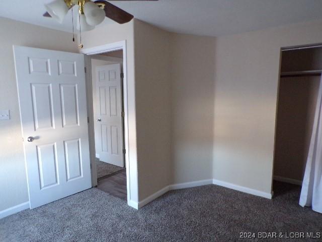 unfurnished bedroom featuring ceiling fan, a closet, and dark carpet