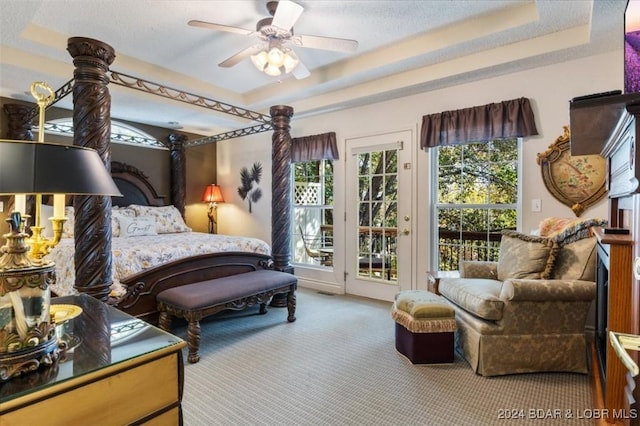 carpeted bedroom with ceiling fan, access to outside, and a tray ceiling