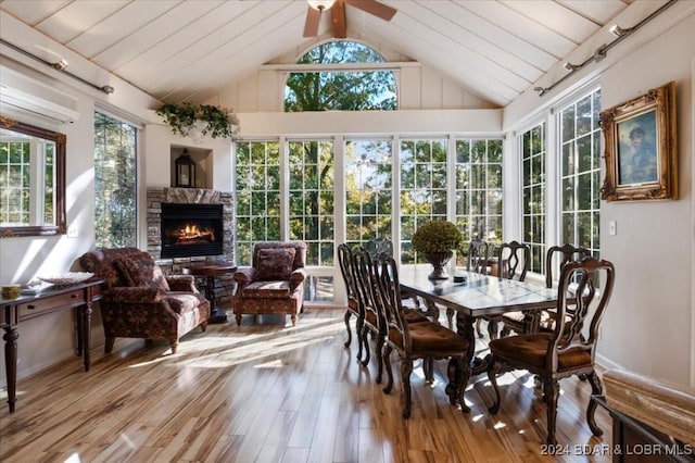 sunroom featuring ceiling fan, a wall mounted air conditioner, lofted ceiling, a fireplace, and wood ceiling