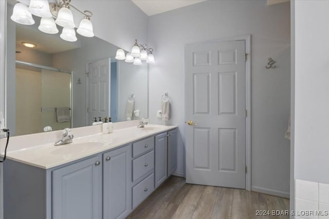 bathroom featuring wood-type flooring, vanity, an inviting chandelier, and an enclosed shower