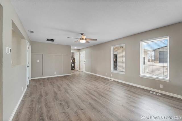 spare room with ceiling fan, a textured ceiling, and light wood-type flooring