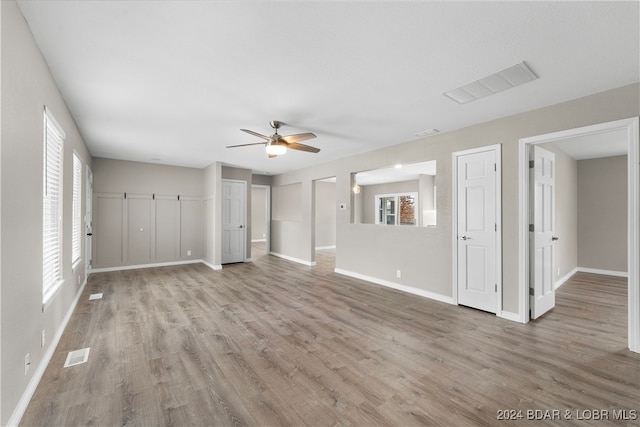 unfurnished living room featuring ceiling fan, a wealth of natural light, and light hardwood / wood-style flooring