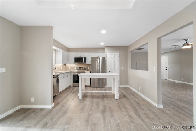 kitchen with ceiling fan, stainless steel appliances, backsplash, light hardwood / wood-style floors, and white cabinets