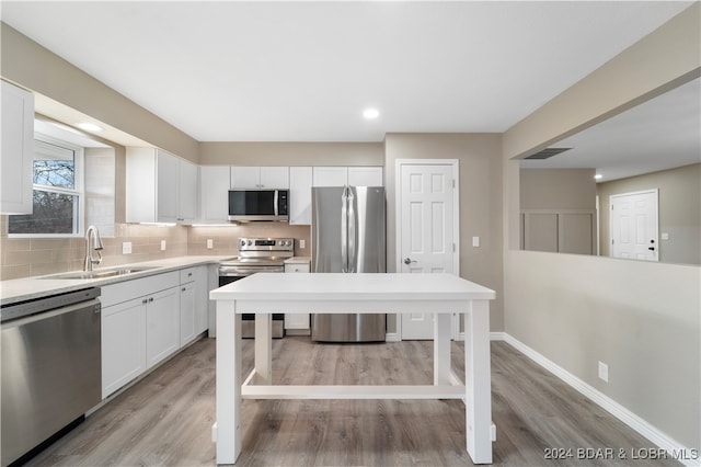 kitchen with white cabinets, sink, appliances with stainless steel finishes, and light hardwood / wood-style flooring