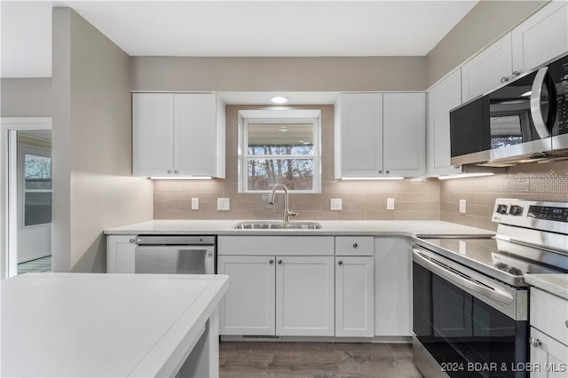 kitchen with backsplash, white cabinets, sink, light hardwood / wood-style flooring, and stainless steel appliances