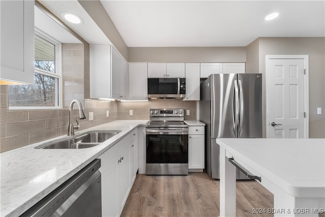 kitchen with light wood-type flooring, white cabinetry, sink, and appliances with stainless steel finishes