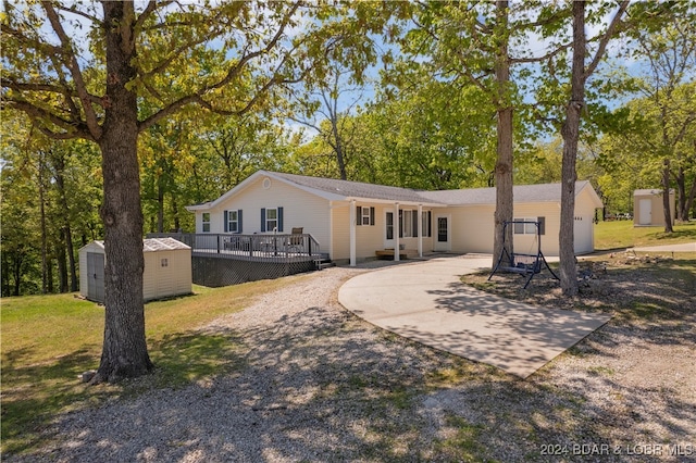 rear view of property with a storage unit, a yard, and a wooden deck