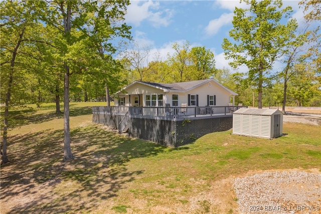 rear view of house with a yard, a deck, and a storage unit