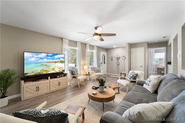 living room with a wealth of natural light, ceiling fan, light hardwood / wood-style floors, and a textured ceiling