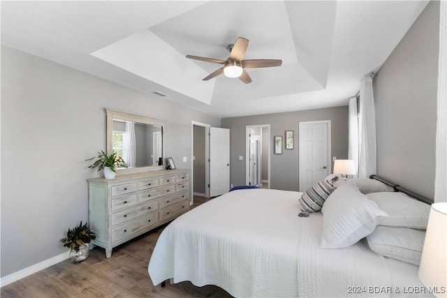 bedroom featuring a raised ceiling, ceiling fan, and dark wood-type flooring