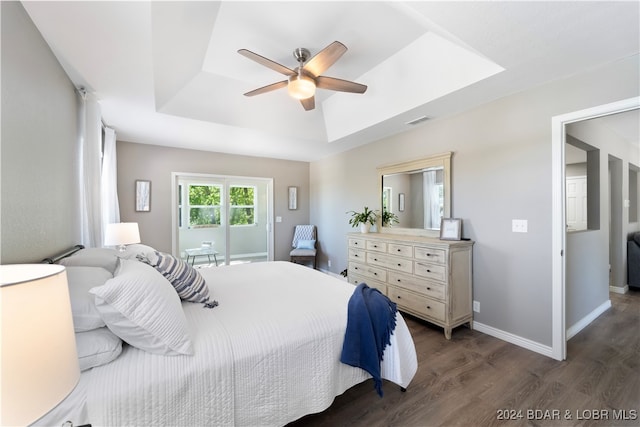 bedroom with dark hardwood / wood-style floors, a raised ceiling, and ceiling fan